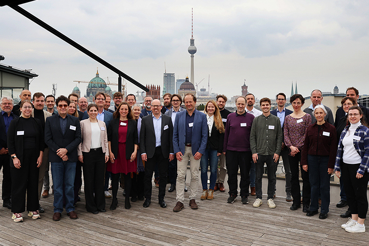 Gruppe von Menschen posiert auf einer Dachterrasse mit Skyline im Hintergrund.